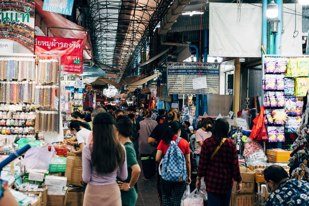 A crowded market in Bangkok with people shopping at various stalls, showcasing vibrant local culture.
