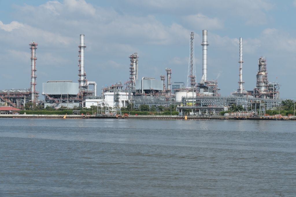 A large oil refinery complex next to the water with cloudy skies.