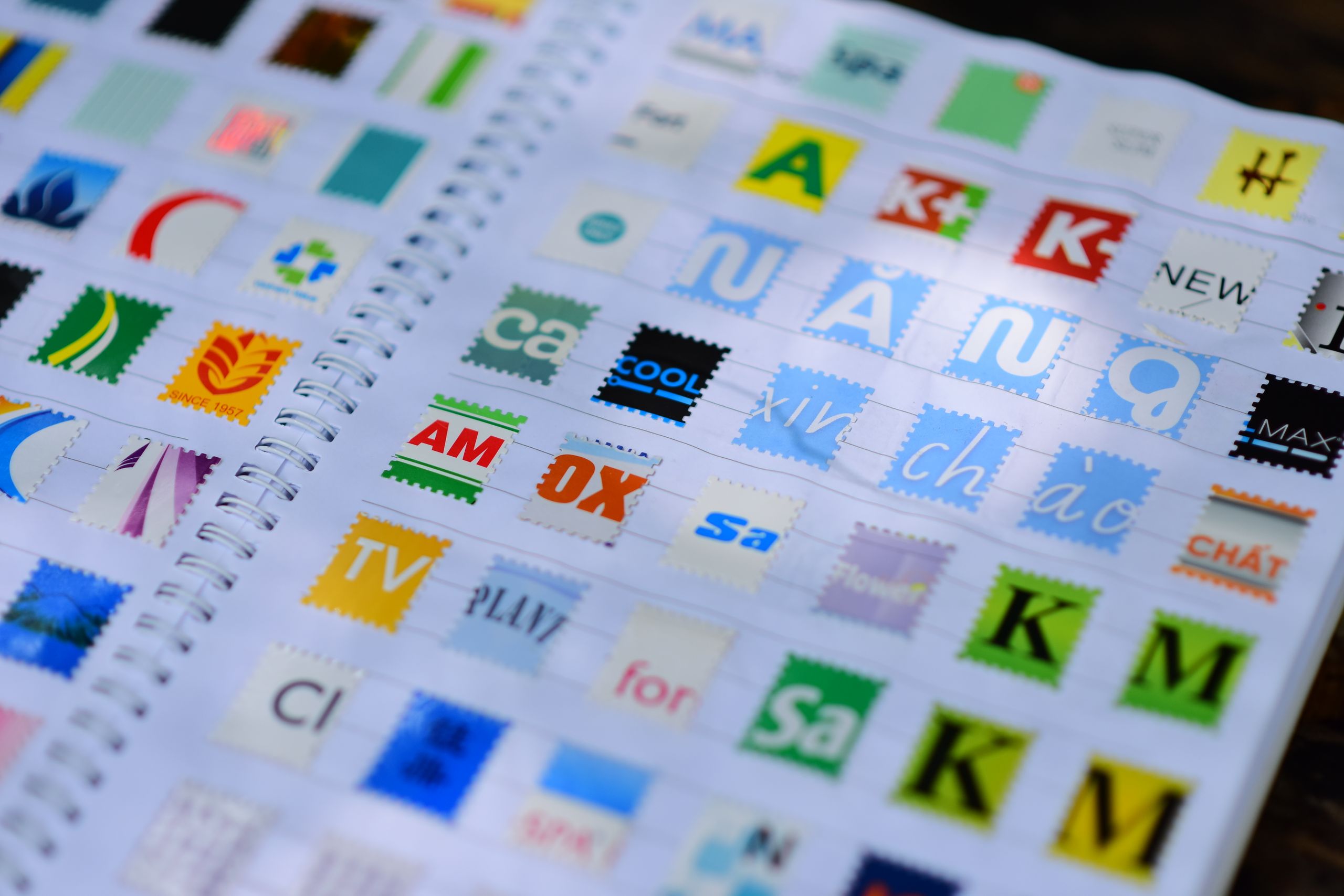 A vibrant mix of colorful stamps displayed in a spiral notebook, showcasing diverse design elements.